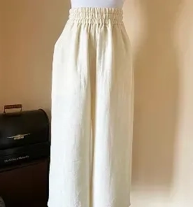 Vネックとフロントプリーツが特徴の白トップス。アシンメトリーな裾が動きを演出します。